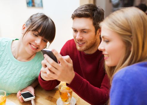 people, leisure, friendship and technology concept - group of happy friends with smartphones meeting at cafe and drinking tea