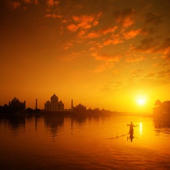 Taj Mahal in Agra, India in golden sunset with silhouette of fisherman.