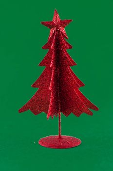Little, red metallic christmas tree on green background