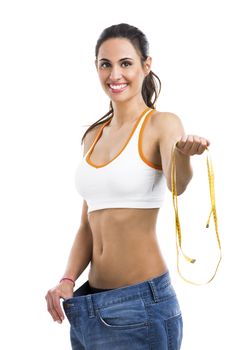 Woman with large jeans in dieting concept holding a measuring tape