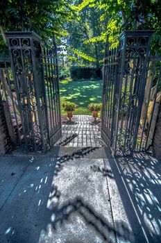 Classical design black wrought iron gate in a beautiful green garden