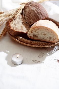 Farm still life. Freshness bread set on white tablecloth near candle