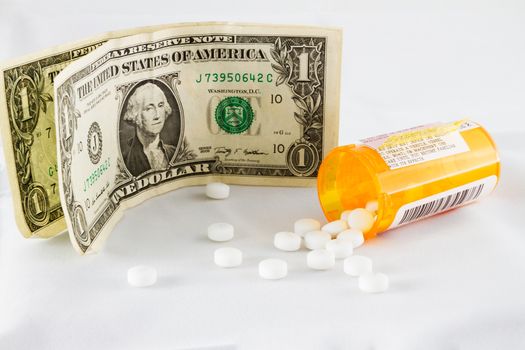 Money with some pills falling out of the bottle