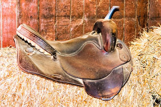 old leather saddle is like a decoration on a pile of hay