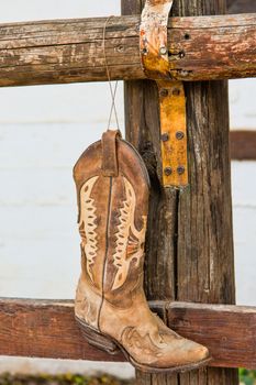 The old cowboy boots  hanging on the bar in front of the stables