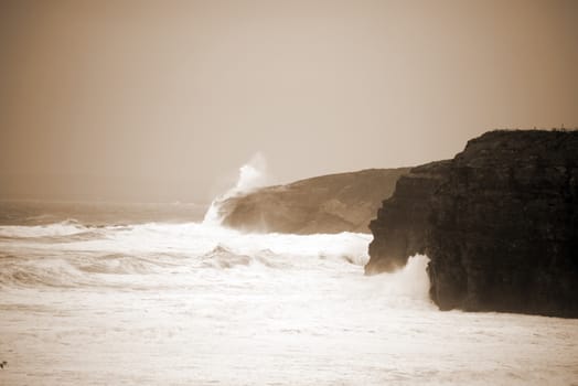 storm waves and cliffs on the wild atlantic way in Ballybunion county Kerry Ireland in sepia