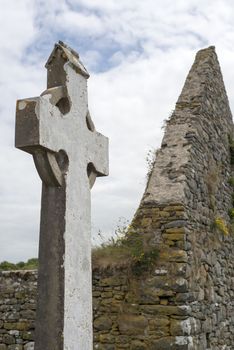 old celtic cross head stone from a grave yard in county kerry ireland next to church ruins