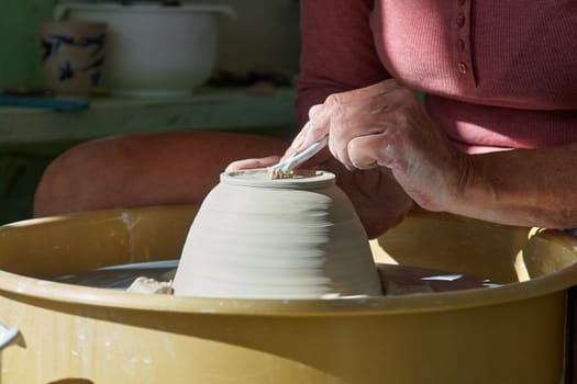 Hands of a potter working on pottery wheel in a workshop studio                               