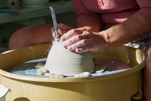 Hands of a potter working on pottery wheel in a workshop studio                               