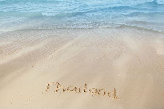 Vacation in Thailand concept - inscription on a beach sand with coming wave