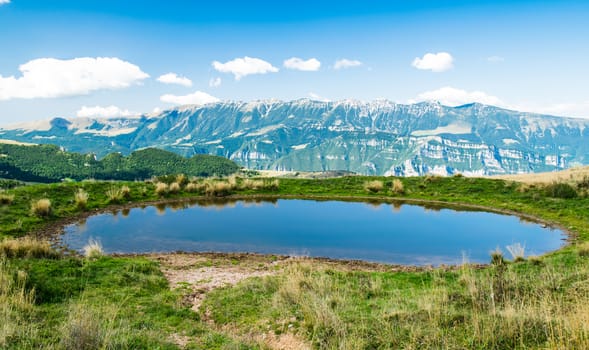 Alpine small pond used for watering the cows that graze on the meadows.