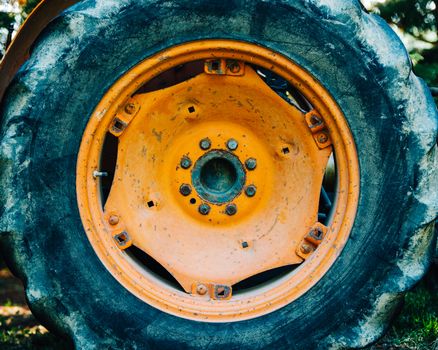 Detail of an old orange tractor wheel. Film emulation and light grain filter applied.