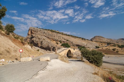 View of ancient historical Cendere Bridge in Adiyaman, built in about 200 AC, on bright blue weather background.