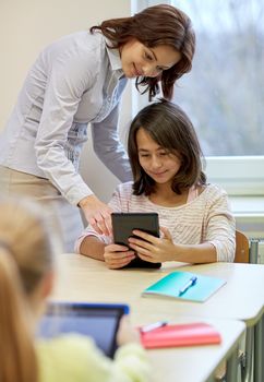 education, elementary school, learning, technology and people concept - little girl with teacher and tablet pc computer in classroom