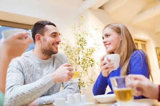 people, leisure, eating and communication concept - happy couple meeting and drinking tea or coffee at cafe