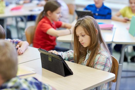 education, elementary school, learning, technology and people concept - little schoolgirl with tablet pc computer on break in classroom