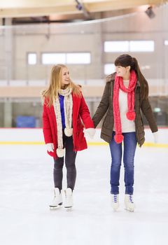 people, women, friendship, sport and leisure concept - two happy girls friends on skating rink