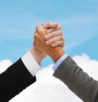 business, people and competition concept - close up of two people hands armwrestling over blue sky and white cloud background