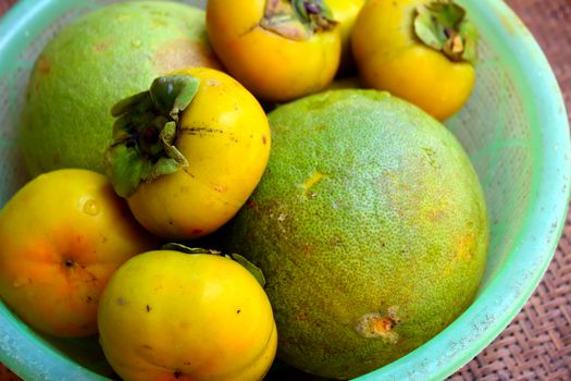 The persimmons and grapefruit in the basket