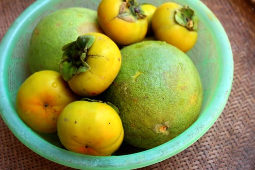 The persimmons and grapefruit in the basket