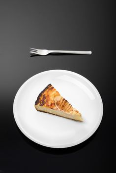 White plate with piece of pear pie on and a fork beside isolated on dark background.