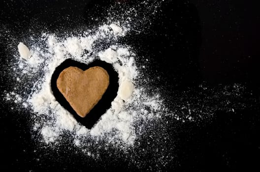 Gingerbread heart with almond and flour isolated on black background.