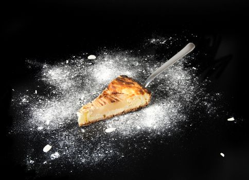 Piece of pear pie on the metal cake shovel isolated on black background.