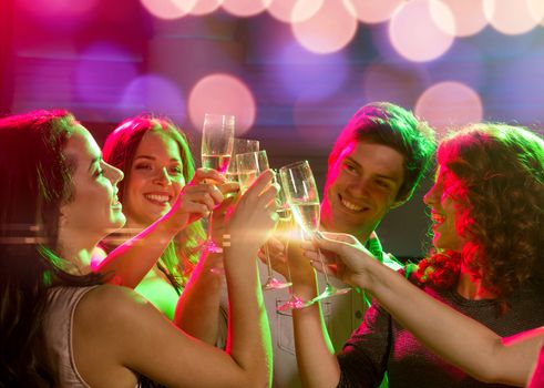 party, holidays, celebration, nightlife and people concept - smiling friends with glasses of champagne in club