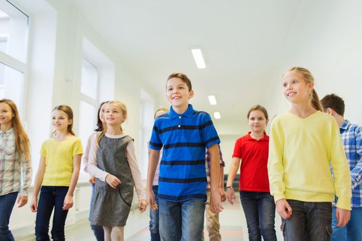 education, elementary school, drinks, children and people concept - group of smiling school kids walking in corridor