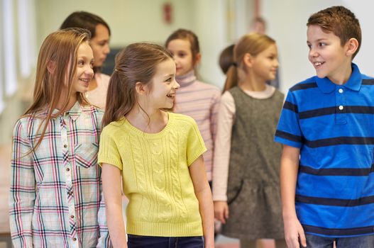 education, elementary school, drinks, children and people concept - group of smiling school kids walking in corridor