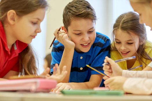 education, elementary school, learning and people concept - group of school kids with pens and papers writing in classroom