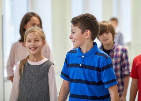 education, elementary school, drinks, children and people concept - group of smiling school kids walking in corridor