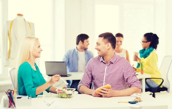 startup, education, fashion, food and office concept - smiling fashion designers having lunch at office