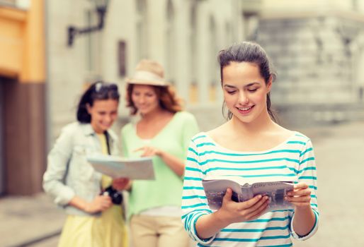 tourism, travel, holidays and friendship concept - smiling teenage girls with city guide, map and camera outdoors