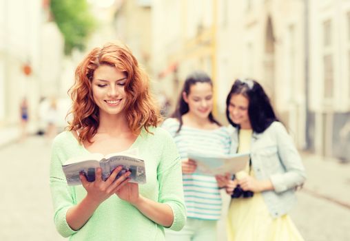 tourism, travel, holidays and friendship concept - smiling teenage girls with city guide, map and camera outdoors
