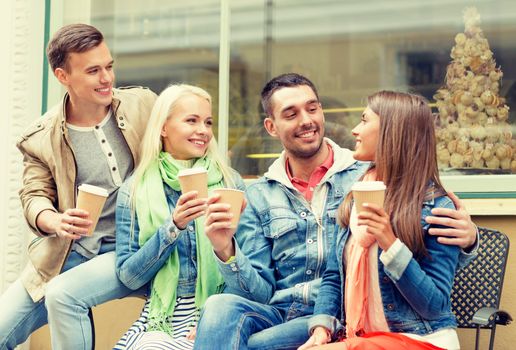 friendship, travel, drink and vacation concept - group of smiling friends with take away coffee