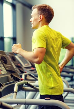 sport, fitness, lifestyle, technology and people concept - smiling man exercising on treadmill in gym