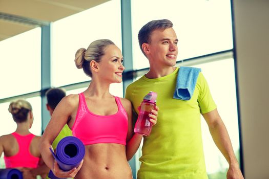 sport, fitness, lifestyle and people concept - smiling couple with water bottles in gym