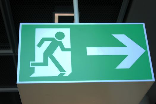 green emergency exit sign showing the way to escape