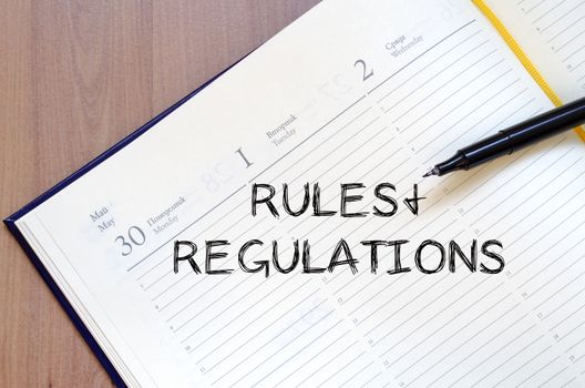 Rules and regulations text concept write on notebook with pen