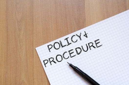 Policy and procedure text concept write on notebook with pen