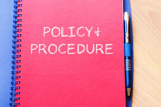 Policy and procedure text concept write on notebook with pen