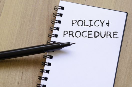 Policy and procedure text concept write on notebook with pen