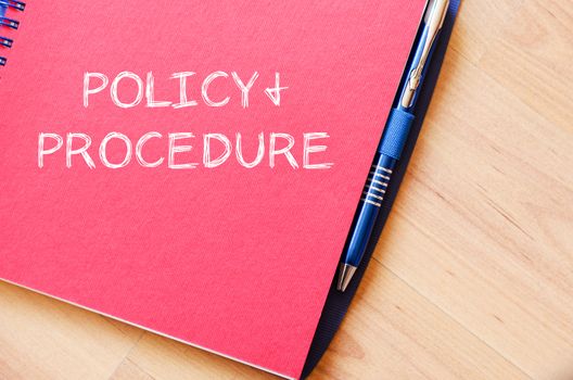 Policy and procedure text concept write on notebook with pen