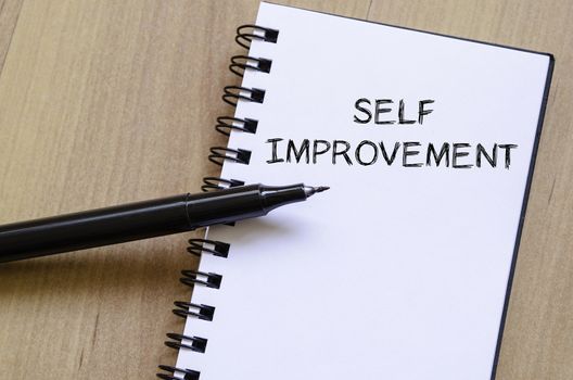 Self improvement text concept write on notebook with pen