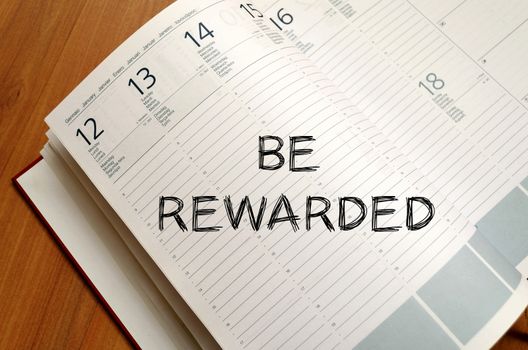 Be rewarded text concept write on notebook with pen