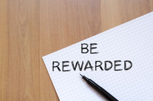 Be rewarded text concept write on notebook with pen