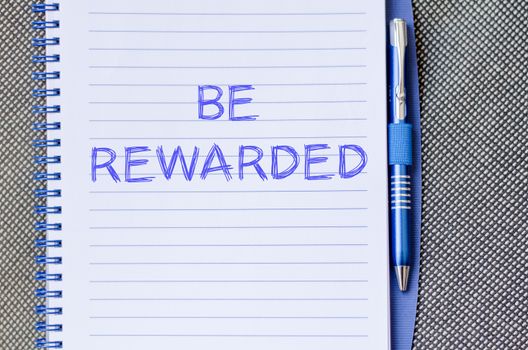 Be rewarded text concept write on notebook with pen