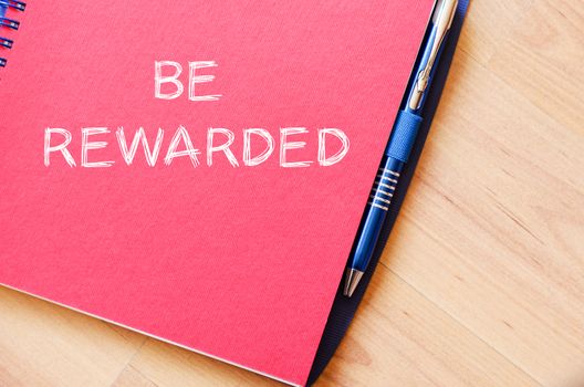 Be rewarded text concept write on notebook with pen