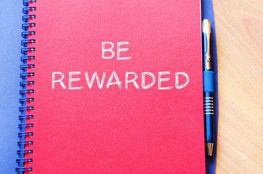 Be rewarded text concept write on notebook with pen